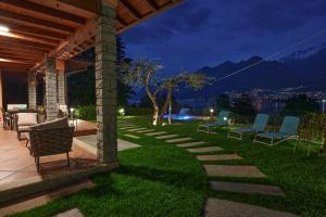 a patio with chairs on a lawn at night at Villa Vittoria with private seasonal heated pool & shared sauna - Bellagio Village Residence in Oliveto Lario