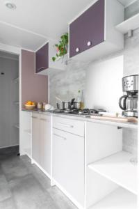a white kitchen with white counters and purple cabinets at Bontempo Village in Piriac-sur-Mer