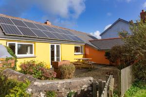 a yellow house with solar panels on the roof at The Milking Parlour in Hartland