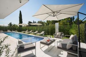 a patio with an umbrella and chairs and a pool at Calma Ii in Starigrad