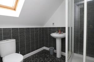 a bathroom with a toilet and a sink at Modern 4 Bed House with Parking in Swadlincote