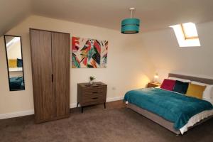 een slaapkamer met een bed en een houten kast bij Modern 4 Bed House with Parking in Swadlincote