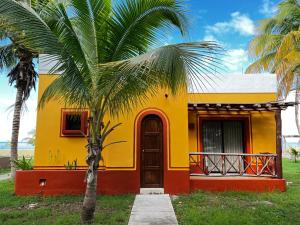 a yellow and red house with a palm tree at Hotel Manglares in Celestún
