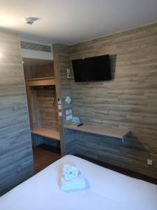 a room with a bed and a tv on a wall at Acotel Confort in Le Pontet