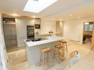 a kitchen with a large island with bar stools at Dazie Cottage in Broadway