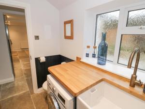 a kitchen with a sink and a bottle on a counter at Dazie Cottage in Broadway +21 photos