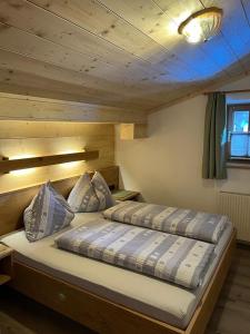 two beds in a room with wooden walls at Wirtshäusl Maria Alm in Maria Alm am Steinernen Meer