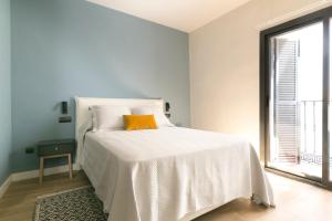 ein weißes Schlafzimmer mit einem Bett mit orangefarbenem Kissen in der Unterkunft Aqua Apartments Málaga in Málaga