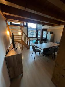 ein Wohnzimmer mit einem Tisch, Stühlen und einem TV in der Unterkunft Duplex St Gervais rooftop - 500m des télécabines in Saint-Gervais-les-Bains