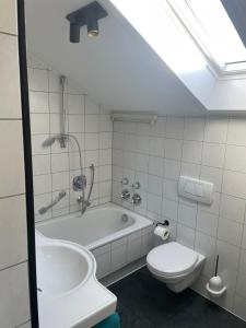 a bathroom with a tub and a toilet and a sink at Lichtdurchflutete Dachgeschoss-Wohnung mit großem Balkon in Bruckmühl