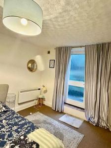 a bedroom with a bed and a large window at Seafront Balcony Apartment in Hastings