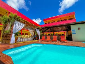 a swimming pool in front of a building with chairs at Pousada Villa Marceneiro Beach in Passo de Camarajibe