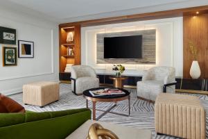 a living room with a couch and chairs and a tv at The Fairmont Washington DC in Washington, D.C.