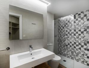 a bathroom with a sink and a toilet and a mirror at Apartamentos Torre del Reloj in Jaca