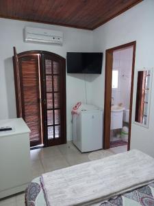 a room with a room with a refrigerator and a television at Suíte em Caraguá in Caraguatatuba