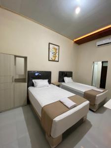 a bedroom with two beds and a mirror at Nawasena Guesthouse Jogja in Kalasan