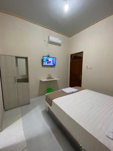 a bedroom with a bed and a tv on the wall at Nawasena Guesthouse Jogja in Kalasan
