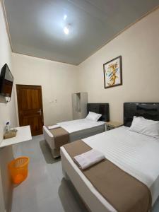 a hotel room with two beds and a television at Nawasena Guesthouse Jogja in Kalasan