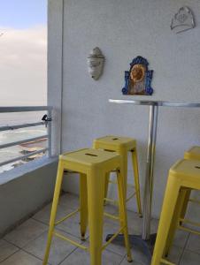 dos taburetes amarillos y un bar con vistas al océano en Departamento en Reñaca, en Viña del Mar