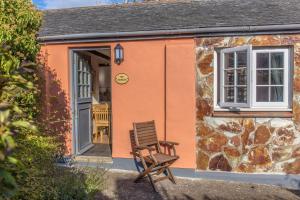 a chair sitting outside of a small cottage at The Stables in Hartland