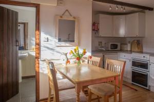 a kitchen with a wooden table with chairs and a dining room at The Stables in Hartland