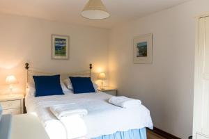 a bedroom with a large white bed with blue pillows at The Stables in Hartland