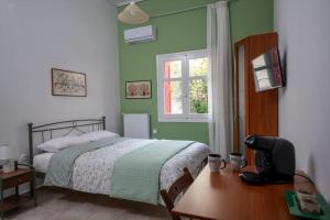 a bedroom with a bed and a desk with a television at Delphian Colors - Green Edition in Delphi