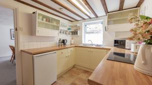 a kitchen with white cabinets and a ceiling at Puddle Cottage in Southwold