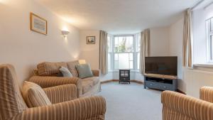 a living room with two couches and a flat screen tv at Puddle Cottage in Southwold