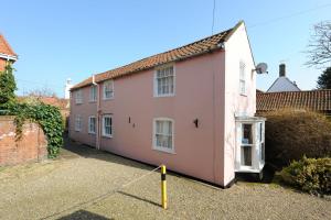 a pink house in a parking lot in a yard at Puddle Cottage in Southwold