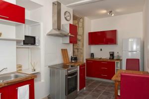 una pequeña cocina con armarios rojos y fregadero en Le gîte de l'Abbaye - Beaulieu-lès-Loches, en Beaulieu-lès-Loches