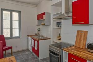 - une cuisine avec des placards rouges et un évier dans l'établissement Le gîte de l'Abbaye - Beaulieu-lès-Loches, à Beaulieu-lès-Loches