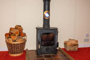 a black stove with a basket of wood at Ormsaig Byre in Beach