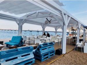 a white pavilion with blue chairs and tables on the beach at apartamento exclusivo muy cerca ciudad Barcelona in Badalona
