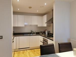 a kitchen with white cabinets and black appliances at Homestay Room in Apartment with Stunning Thames River View in London