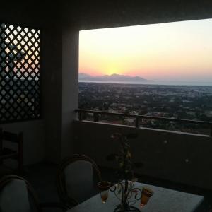 einen Blick auf den Sonnenuntergang von einem Zimmer mit einem Tisch und Stühlen in der Unterkunft Hercules Hills Sea View Villas in Kos-Stadt