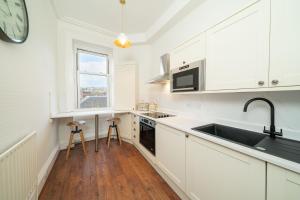 cocina con armarios blancos, fregadero y ventana en Central Apartments - Colonial en Blairgowrie