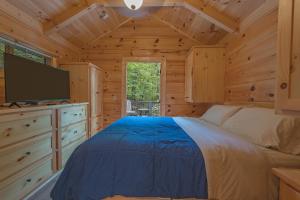 a bedroom with a bed and a flat screen tv at Papa Cabin Tiny Log Home Comfort In Rustic Bliss in Chattanooga