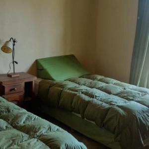 two beds in a room with a table and a lamp at La Calandria in Los Hornillos