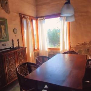 comedor con mesa, sillas y ventana en La Calandria en Los Hornillos