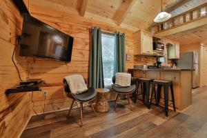 a kitchen with bar stools and a flat screen tv in a log cabin at River Cabin Hot Tub & Swim Spa Near Downtown in Chattanooga