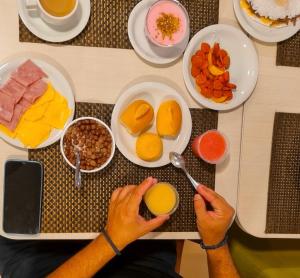 uma pessoa está sentada numa mesa com uma bandeja de comida em Gree Hotel em São Luís