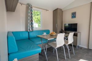 un soggiorno con divano blu, tavolo e sedie di Camping les falaises de Toussaint a Toussaint