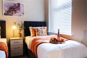 1 dormitorio con 1 botella de vino y fruta en la cama en 2 Bedroom 1 Bathroom Town Center Apartment With FREE Parking By REDWOOD STAYS, en Basingstoke