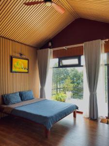 - une chambre avec un lit bleu et une grande fenêtre dans l'établissement JE T'AIME VILLA - Khu nghỉ dưỡng nhà vườn nằm giữa thiên nhiên bao la hoa cỏ, à Bảo Lộc