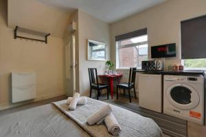 a living room with a washing machine and a table at Modern Studio Apartment - Vibrant Abbeydale Rd, FREE Parking, Pet Friendly, Netflix in Sheffield