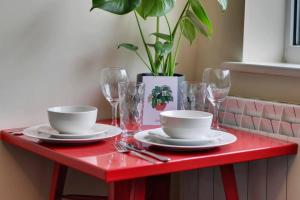 a red table with plates and glasses and a plant at Modern Studio Apartment - Vibrant Abbeydale Rd, FREE Parking, Pet Friendly, Netflix in Sheffield