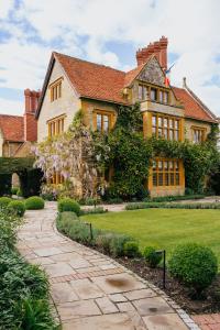 une grande maison avec une passerelle devant elle dans l'établissement Le Manoir aux Quat'Saisons, A Belmond Hotel, Oxfordshire, à Great Milton
