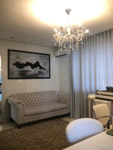 a living room with a couch and a chandelier at Paracatu Plaza Hotel in Paracatu