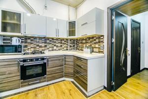 cocina con armarios blancos y nevera negra en Apartment Armani Lux en Bakú